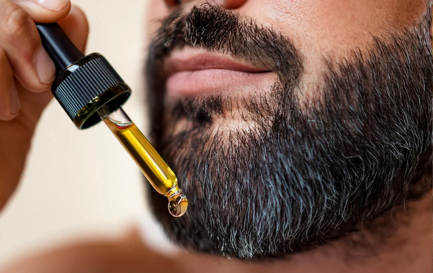 Primer plano de un hombre aplicando Aceite de Oliva para la Barba con un gotero